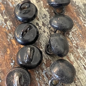 May include: Eight black buttons with silver loops. The buttons are round and have a smooth, shiny finish.