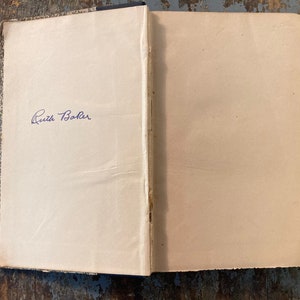 May include: A close-up of the inside cover of a book with a handwritten inscription that reads "Ruth Baker".