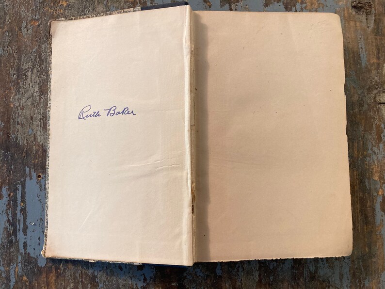 May include: A close-up of the inside cover of a book with a handwritten inscription that reads "Ruth Baker".