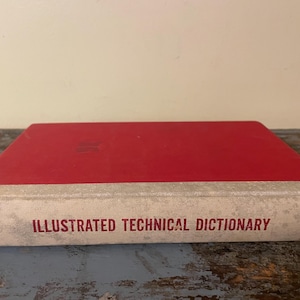 May include: A red hardcover book with the title "Illustrated Technical Dictionary" printed in white on the spine. The book is part of the "Remarkable Library" series.