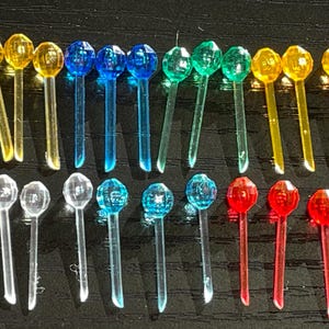 May include: Assortment of colorful Christmas light bulbs with different colored tips. The bulbs are arranged in rows and include yellow, green, blue, and red.