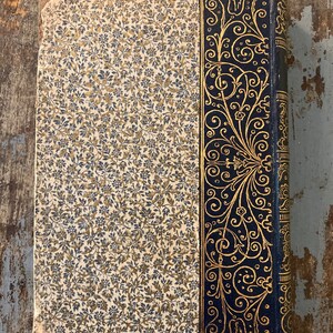 May include: The cover of an old book with a floral pattern and a decorative gold and black border.