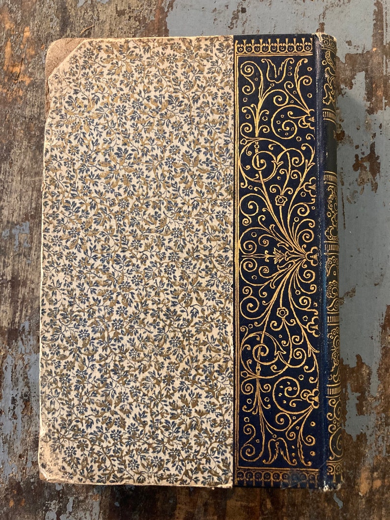 May include: The cover of an old book with a floral pattern and a decorative gold and black border.