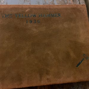 May include: A brown leather-bound book with the title "The Yellow Hammer" and the year "1930" printed on the front cover. A small hammer symbol is printed in the bottom right corner.
