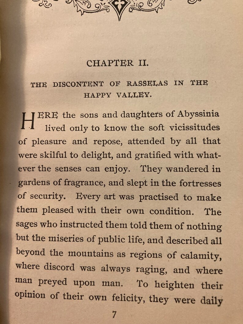 May include: A page from a book titled "The Discontent of Rasselas in the Happy Valley." The text describes the sons and daughters of Abyssinia who live in a valley where they are shielded from the hardships of the outside world.
