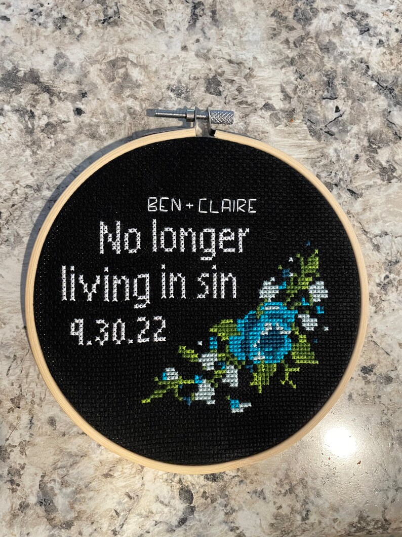 Puede incluir: Aro de bordado negro con texto blanco que dice "Ben + Claire No longer living in sin 9.30.22" y un dise&ntilde;o floral azul y verde.