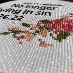 Puede incluir: Aro de bordado blanco con el texto "No longer living in sin 12.22" en hilo negro. El aro est&aacute; decorado con un dise&ntilde;o floral en hilo rosa, verde y marr&oacute;n.