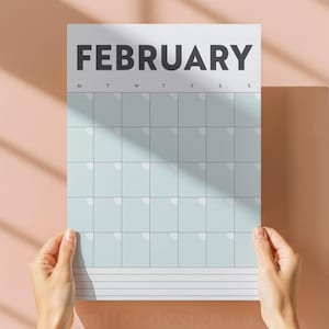 Peut inclure: Une page de calendrier blanche avec le mois de février imprimé en gras, en noir. La grille du calendrier est bleu clair avec des cases blanches pour chaque jour. Le calendrier est tenu par des mains sur un fond rose.