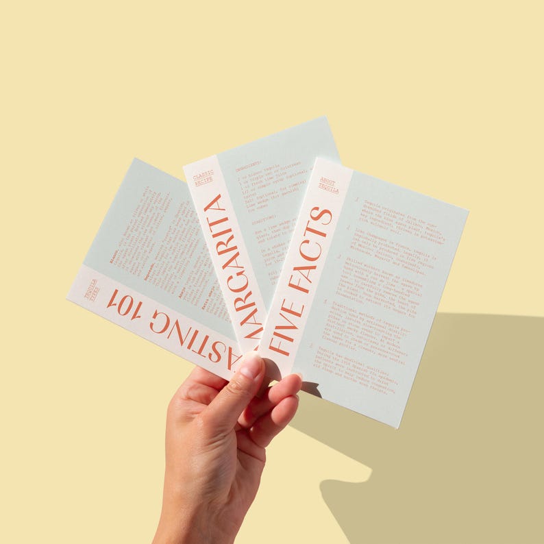 May include: Three cards with text on them. The top card says "Five Facts" in a light orange font. The middle card says "Margarita" in a light orange font. The bottom card says "Tasting 101" in a light orange font.