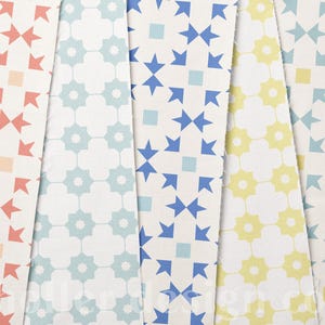 May include: Five fabric swatches with repeating geometric patterns in various colors. The patterns include starburst and floral designs in coral, light blue, blue, yellow, and white. The fabric is likely cotton or a similar material.