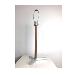 May include: A chrome and wood table lamp with a simple design. The lamp has a wooden base and a chrome shade.