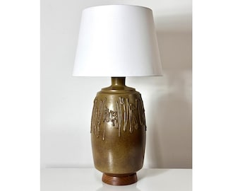 May include: A mid-century modern table lamp with a brown ceramic base featuring a textured design and a white fabric lampshade.