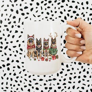 May include: White ceramic mug with a Christmas-themed design featuring four German Shepherd dogs wearing Santa hats and reindeer antlers. The dogs are sitting in a row and holding presents.