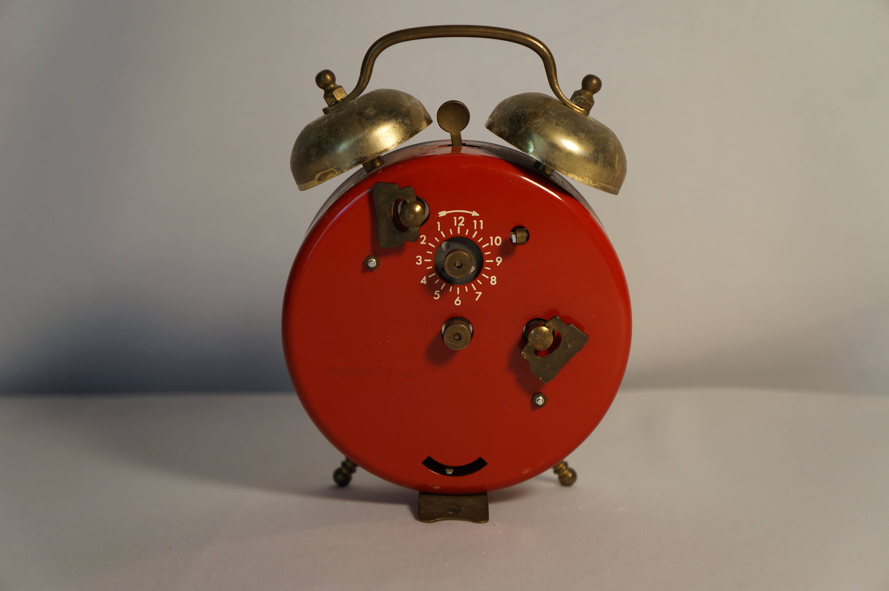 Early 60s steel wind up alarm clock, fireengine red with skeleton face