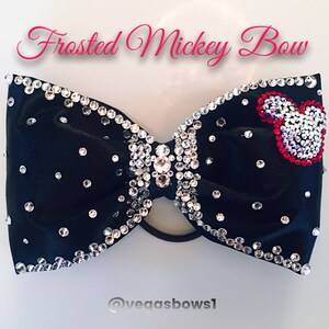 May include: Black velvet bow with silver rhinestones and a red and silver Mickey Mouse head design. The bow is tied with a black elastic band.