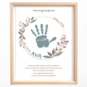 Op de afbeelding: Ingelijste print met een licht houten frame. De print toont een handafdruk in een cirkel, omringd door bloemmotieven. Tekst bevat "A Heavenly Handprint", "John 11:25" en "Loves AVA". Een gedicht is eronder afgedrukt.