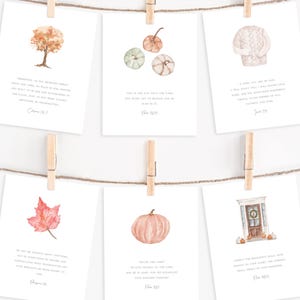 May include: Six white cards with watercolor illustrations of fall themes, including a tree, pumpkins, a sweater, a leaf, a pumpkin, and a door. Each card is clipped to a string with a wooden clothespin and features a Bible verse.