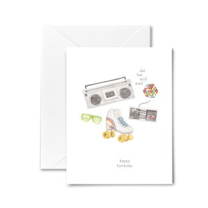 May include: A birthday card with a retro theme. The card features a boombox, roller skates, a video game controller, and a Rubik's cube. The text on the card reads "old but still cool" and "happy birthday".