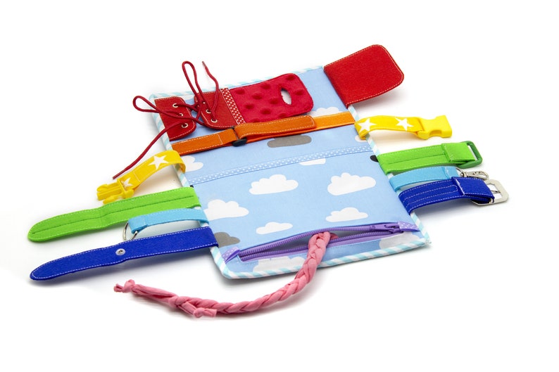 Puede incluir: Un libro de actividades de tela azul y blanco con una variedad de texturas y cierres para que los ni&ntilde;os exploren. Cuenta con una cremallera, cordones, hebillas y velcro.