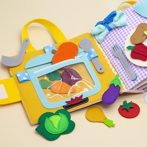 以下が含まれることがあります： ニンジン、ナス、トマト、キャベツなど、さまざまな食品が描かれた子供向けのフェルト製の本。この本には、ジッパー付きのポケットと透明なプラスチック製の窓があります。