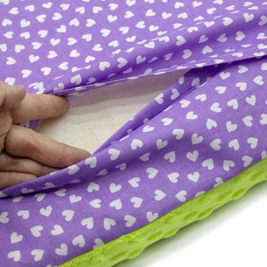 May include: A purple cushion with a white heart pattern on the fabric. The cushion is filled with a white, fluffy material. The cushion has a green, textured backing.