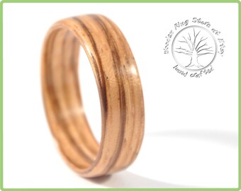 May include: A handcrafted wooden ring, close-up view. The ring has a striped pattern in shades of brown and tan. The ring is polished and smooth. The ring is a piece of jewellery.