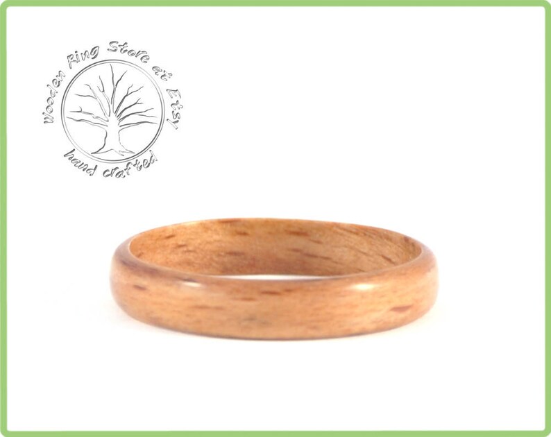 May include: A close-up of a wooden ring with a natural wood grain finish. The ring is smooth and polished, and it has a warm, natural color.
