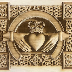Op de afbeelding: Een houten carving van een Keltisch knoopontwerp met twee handen die een hart met een kroon erop omvatten. Het ontwerp is omgeven door een rand van Keltische knopen.