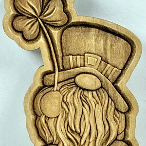 May include: A wooden carving of a leprechaun holding a four-leaf clover. The leprechaun is wearing a hat and has a long beard.