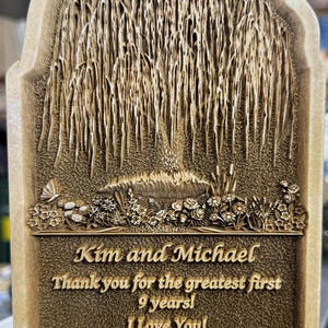 May include: A wooden plaque with a carved weeping willow tree design. The plaque has a personalized message that reads "Kim and Michael Thank you for the greatest first 9 years! I Love You! We may bend but we'll never break October 16, 2025".