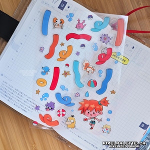 May include: Transparent sticker sheet featuring vibrant cartoon illustrations of sea creatures, characters, and shapes. The sheet includes the word "MONDAY" and the website "PIXELPALETTE.CA".