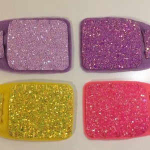 May include: Four felt beds with glitter fabric. Two beds are purple, one is yellow, and one is pink.