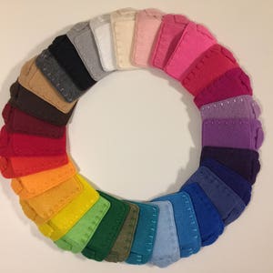 Op de afbeelding: Een regenboog van viltvierkanten gerangschikt in een cirkel. De vierkanten zijn in tinten rood, oranje, geel, groen, blauw, indigo en violet.