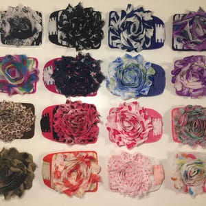 May include: A collection of 15 handmade fabric flower hair clips in various colours and patterns, including floral, leopard print, and polka dots.