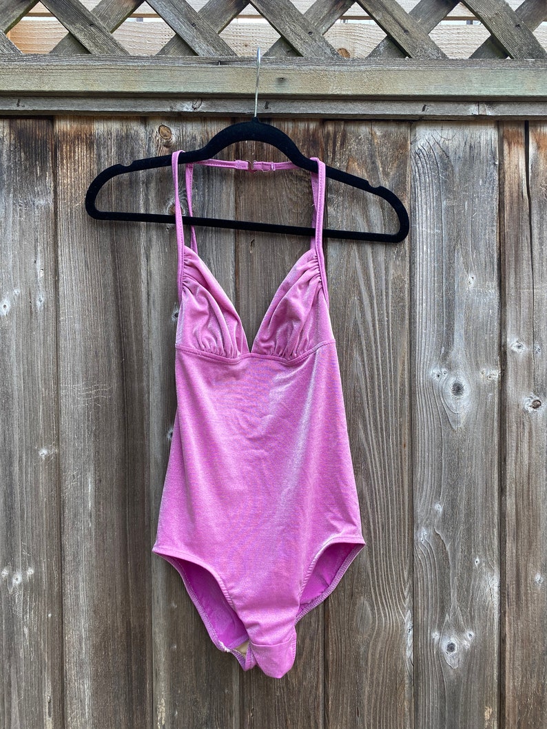 May include: A pink halter-style swimsuit with a V-neckline and a shiny finish.