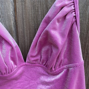 May include: Close-up of a purple velvet top with a V-neckline and adjustable straps.