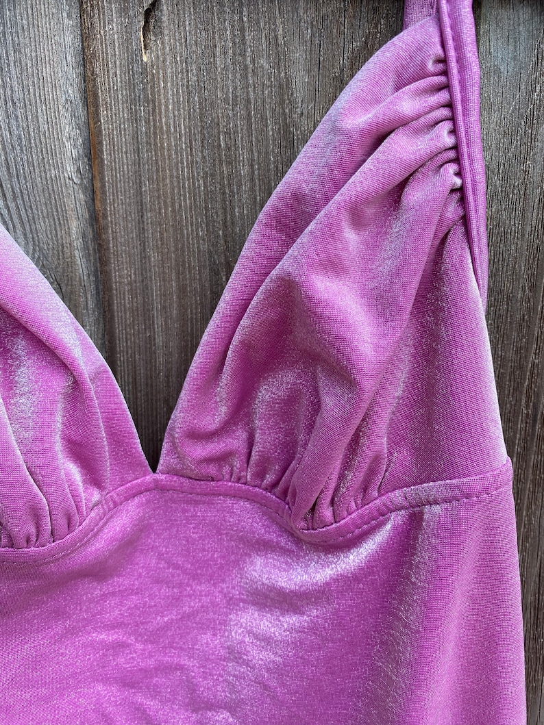 May include: Close-up of a purple velvet top with a V-neckline and adjustable straps.