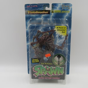 May include: A plastic package containing a Spawn Vertebreaker action figure. The figure is a skeletal, articulated monster with a red and brown color scheme. The packaging features the Spawn logo and the text "Deluxe Edition Ultra-Action Figures".