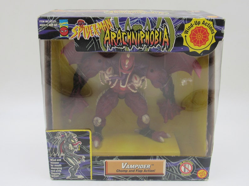 May include: A red and black action figure of a monster called Vampider from the Spider-Man: Arachnophobia toy line. The figure has wings, a large mouth, and a long tongue. The packaging features a spider web design and the text "Wind-Up Actions".