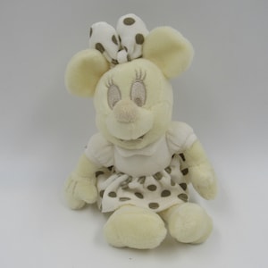 May include: A plush toy of a white mouse with brown polka dots on its dress and bow. The mouse has a white dress with brown polka dots and a brown polka dot bow on its head.