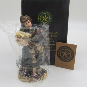 Könnte beinhalten: Eine Figur einer Frau mit Brille und grünem Kleid, die einen Stapel Bücher und Papiere hält. Die Figur ist Teil der Boyd's Bears & Friends The Antique Collection.