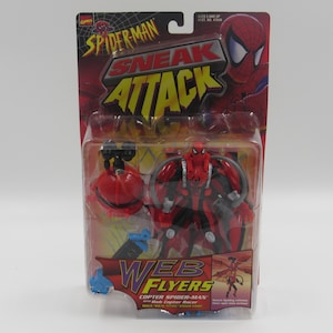 May include: A red and black Spider-Man action figure with a web copter accessory. The figure is packaged in a plastic blister pack with a red, black, and yellow background. The packaging features the text "Spider-Man Sneak Attack Web Flyers Copter Spider-Man with Web Copter Racer".