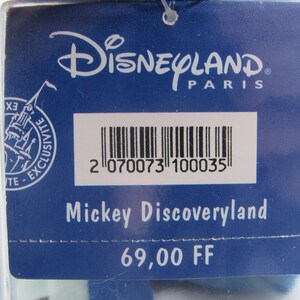 May include: A blue tag with the Disneyland Paris logo and the text "Mickey Discoveryland". The tag has a barcode and the text "Exclusive".