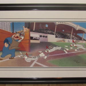 Puede incluir: Impresión artística enmarcada de dibujos animados con Bugs Bunny deslizándose hacia la base, con un receptor y un estadio de béisbol en el fondo. La obra de arte está en un marco negro y tiene un borde blanco.