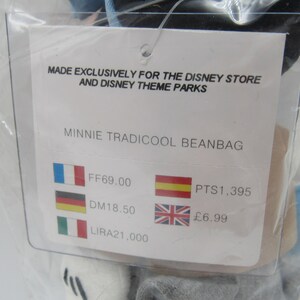 May include: A white tag with black text that reads "Made exclusively for the Disney Store and Disney Theme Parks" and "Minnie Tradicool Beanbag". The tag also shows prices in different currencies: FF69.00, DM18.50, LIRA21,000, PTS1,395, and &pound;6.99.