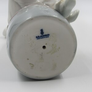 May include: The bottom of a white porcelain figurine with a blue Lladro logo and the number 5271.