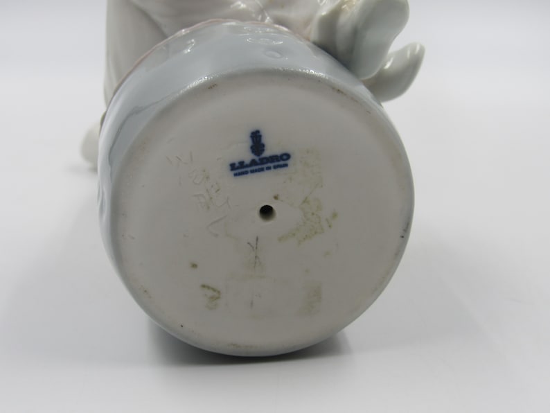 May include: The bottom of a white porcelain figurine with a blue Lladro logo and the number 5271.