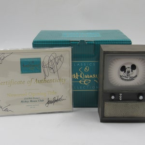 May include: A Disney Classics 50th Anniversary Collection set. It includes a vintage-style television, a certificate of authenticity, and a teal box. The TV displays a Mickey Mouse Newsreel image.