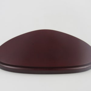 May include: A dark red wooden display stand shaped like an oval. The stand is smooth and has a slightly rounded edge.