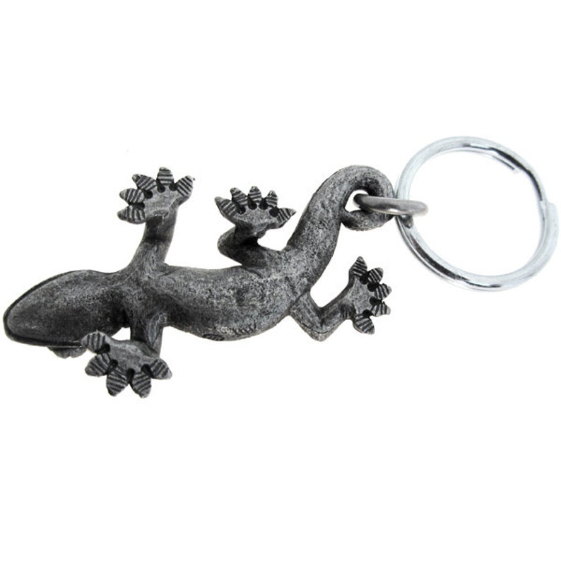 May include: A detailed, grey metal lizard keyring. The lizard is shown crawling, with textured skin and detailed feet. A silver-coloured key ring is attached to the lizard's back, ready for keys.
